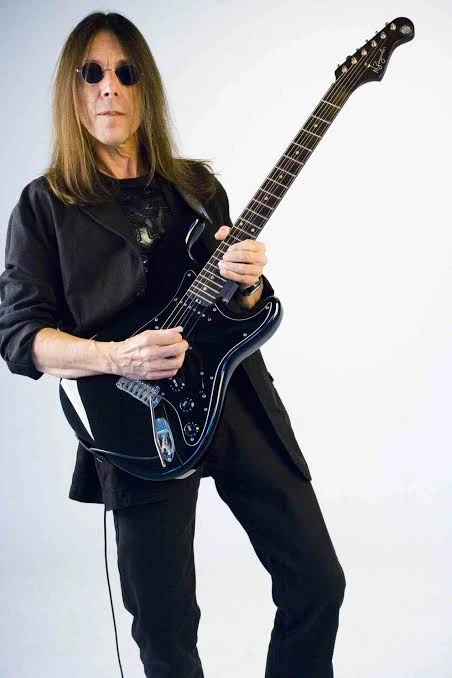 Faiska Borges em pé, segurando uma guitarra preta